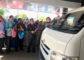 Zaini Hussin (kanan) melekatkan Jalur Gemilang pada sebuah kenderaan pada Majlis Kibar Jalur Gemilang di Wisma Persekutuan, Kota Bharu, Kelantan.UTUSAN/ ROSLIZA MOHAMED