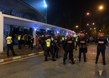 ANGGOTA polis mengawal penyokong pada perlawanan Liga Super di antara Perak FC dan JDT di Stadium Perak semalam. - UTUSAN/ZULFACHRI ZULKIFLI