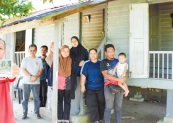 AZLAN Azam (kiri) menunjukkan poskad pelancongan yang memaparkan rumah keluarga mereka yang dikenali dengan Rumah Poskad di Kampung Bugis Beserah, Kuantan. – UTUSAN/NORHAFIZAN ZULKIFLI