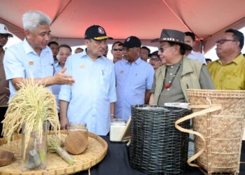 HAJIJI Noor (dua kiri) mendengar taklimat projek daripada Ketua Pegawai Eksekutif Victor Ationg (kiri) di tapak penanaman padi di Kampung Ongkilan, Kota Marudu hari ini.