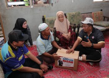 BADRUL Hisham Alias (kanan) menyampaikan bakul makanan kepada seorang penduduk sempena Program Santuni Madani di Kampung Padang Tanjung, Bukit Payong, Kuala Terengganu, hari ini.