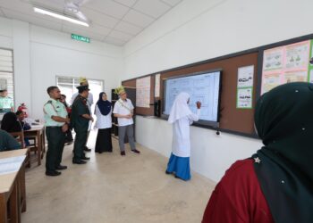 Wong Kah Woh meninjau murid Sekolah Kebangsaan Rancangan Penempatan Semula Banun menjawab pada papan pintar semasa lawatan kerja di Gerik, Perak, hari ini. - UTUSAN/FADZIL ZAINOL