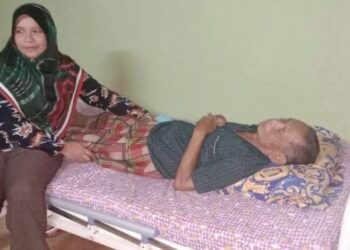 NIK Roslina Nik Mat (kiri) menjaga kebajikan Nik Mat Nik Hassan (berbaring) yang mengalami penyakit buah pinggang tahap empat di Felda Kota Gelanggi Empat di Jerantut, Pahang.
– UTUSAN/HARIS FADILAH AHMAD
