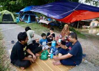SITI Aminah Md. Isa di samping anak-anak dan cucunya berkelah di hadapan rumah mereka yang dinaiki air ketika ditemui di Kampung Padang Teja, Jitra Kubang Pasu. - UTUSAN/ SHAHIR NOORDIN