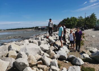 PENDUDUK Sungai Tiang melihat ban yang terjejas akibat air pasang di kampung mereka di Bagan Datuk, Perak, kelmarin. – UTUSAN/AIN SAFRE BIDIN