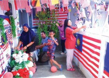 PENDUDUK bergotong-royong memasang Jalur Gemilang di Blok A Rumah Pangsa Lereh, Tanjong Kling, Melaka. – UTUSAN/AMRAN MULUp