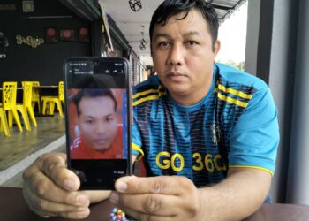 NOOR Syaifuan Abu Talib menunjukkan gambar adiknya, Noor Azmi yang dilaporkan hilang sejak sebulan lalu. - UTUSAN