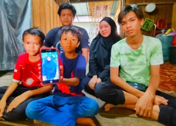 MUHAMAD Riduan Mohd. Yusoff (belakang, kiri) bersama adik-beradiknya menunjukkan gambar ibu mereka yang maut kemalangan semasa ditemui di Chucuh Puteri, Kuala Krai, Kelantan.-UTUSAN/YATIMIN ABDULLAH