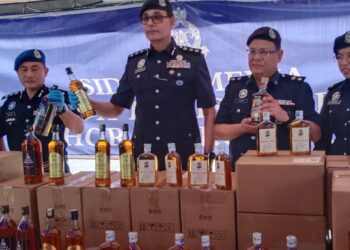 BALVEER Singh Mahider Singh (tengah) menunjukkan arak tiruan yang dirampas daripada Geng Ah Meng dalam sidang akhbar di Balai Polis Tampoi, Johor Bahru.
