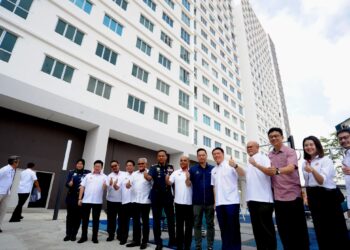 NGA KOR MING bergambar (tengah) berlatarbelakangkan perumahan Residensi PR1MA sempena Majlis Penyerahan Kunci, Pelancaran Bomba Komuniti dan Program Sentuhan Kasih KPKT Residensi PR1MA Taman Pelangi Indah, Johor Bahru.