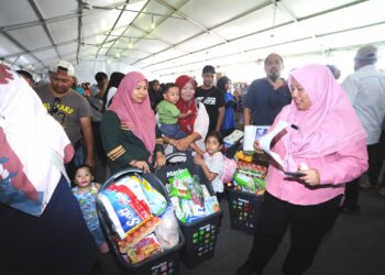 LILIS SASLINDA Pornomo (kanan) beramah mesra  dengan orang ramai yang membeli barangan sempen Program Jualan Rahmah di Stadium MBPG, Pasir Gudang.