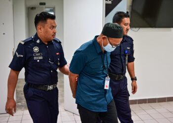 ISHAK Abdul Rahman (tengah) yang dipenjarakan lima tahun atas pertuduhan melakukan amang seksual fizikal terhadap seorang remaja perempuan dibawa keluar dari Mahkamah Sesyen Kuala Terengganu, hari ini. - UTUSAN/PUQTRA HAIRRY ROSLI