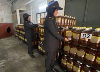ANGGOTA penguatkuasa KPDN Perak memeriksa minyak masak yang dirampas dalam serbuan di syarikat pemborong di Langkap, Teluk Intan semalam. - UTUSAN/IHSAN KPDN PERAK
