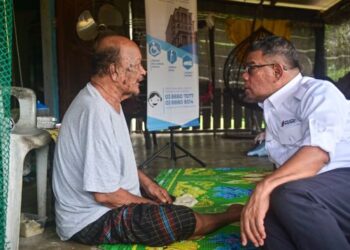 SAIFUDDIN Nasution Ismail (kanan) beramah mesra dengan seorang penduduk pada program MEKAR Penyerahan Dokumen Pengenalan Diri di Kampung Baru Pulau Redang, Kuala Nerus, semalam. - UTUSAN/PUQTRA HAIRRY ROSLI