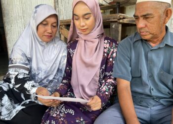 AWANG Mat Nor bersama anaknya, Wan Nur'alyaa Syaza melihat surat tawaran masuk universiti di rumah mereka di  Kampung Tok Bali, Pasir Puteh, Kelantan, semalam. UTUSAN/TOREK SULONG