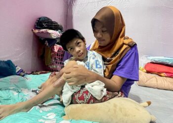 SUHADA Suib memangku Mohd. Afiq Ramadhan Abdullah di Pusat Pemindahan Sementara (PPS) Stadium Sultan Abdul Halim selepas rumah mereka di Kampung Alor Merah dinaiki air di Alor Setar.