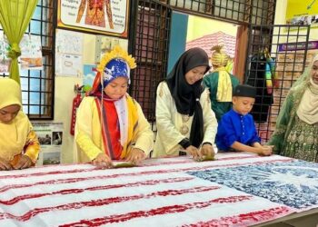 MURID-MURID Sekolah Kebangsaan (SK) Putra menggunakan teknik mengecap dalam menghasilkan Jalur Gemilang gergasi di Kangar, Perlis. – UTUSAN/ASYRAF MUHAMMAD
