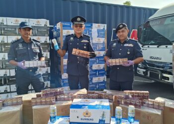 MUHAMMAD Ilyas Queek Abdullah (tengah) menunjukkan minuman keras dan rokok putih yang dirampas hasil serbuan dan pemeriksaan terhadap sebuah lori, kontena dan gudang di Selangor bulan lalu.