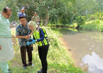 SUHAIMIZAN Bizar (kiri) melihat pegawai JAS mengambil sampel air susulan kejadian air Sungai Gemencheh menjadi hitam di Kampung Tenai, Tampin hari ini.-UTUSAN/NOR AINNA HAMZAH,