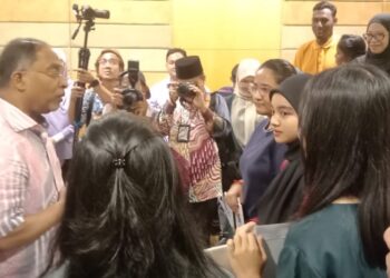 ZAMBRY Abd. Kadir (kiri) beramah mesra dengan bakal mahasiswa IPTA yang menerima Wang Pendahuluan Pinjaman di Seri Manjung, hari ini. - UTUSAN