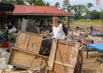 ABU Bakar Othman melihat sebahagian daripada perabot kayu yang rosak dalam kejadian banjir di rumahnya di Kampung Padang Luar, Kubang Pasu, Kedah, semalam. – UTUSAN/SHAHIR NOORDIN