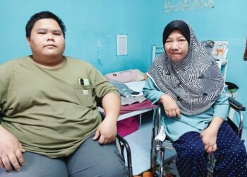 MUHAMAD Sayyid Azinuddin Mohd. Zin (kiri) dan Rosyati Mohd. Noor terpaksa menggunakan kerusi roda di Rumah Kos Rendah Peringkat 3 dan 4 di Jerantut, Pahang. – UTUSAN/HARIS FADILAH AHMAD