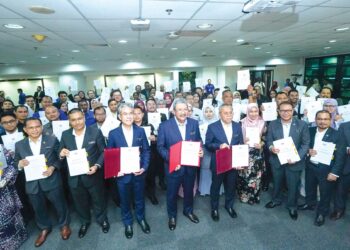 WAN Ahmad Dahlan Abdul Aziz (tengah) bersama penjawat awam menunjukkan borang Opsyen SSPA yang ditandatangani pada majlis menandatangani Opsyen SSPA di JPA Putrajaya, semalam. – UTUSAN/FAISOL MUSTAFA