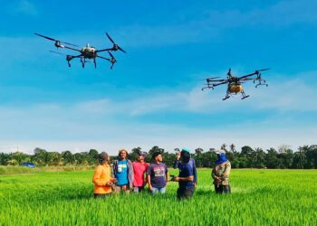 SEKUMPULAN pesawah menunjukkan dron yang mereka gunakan untuk kerja-kerja menabur baja dan menyembur racun di sawah padi mereka di Parit 9,  Sungai Manik  dekat Pasir Salak di Perak, semalam. 
– UTUSAN/AIN SAFRE BIDIN