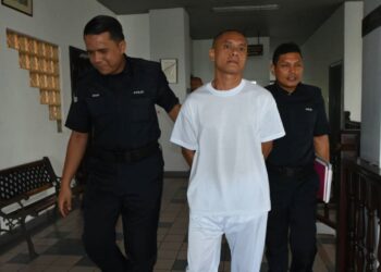 TERTUDUH diiringi anggota polis ketika dihadapkan ke Mahkamah Tinggi, Ayer Keroh, Melaka. - UTUSAN/MUHAMMAD SHAHIZAM TAZALI