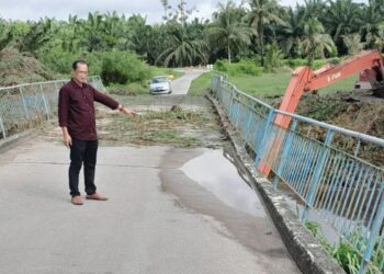 MUSLIM Jupri menunjukkan keadaan Jambatan Parit Rambai, Sungai Sanglang, Pontian yang tidak selamat dilalui akibat rempuhan gumpalan rumput dan sampah-sarap.