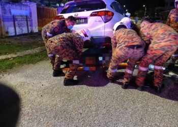 ANGGOTA bomba mengeluarkan mayat mangsa yang terperosok di bawah kereta dalam kemalangan di Tambun di Ipoh hari ini. - UTUSAN/IHSAN JBPM