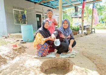 ZAUYAH Ahmad (kanan) menunjukkan mata air yang timbul di halaman rumahnya di Kampung Lanai, Baling, Kedah.