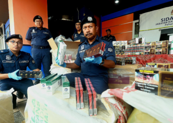 MOHD ASRI Seman (kanan) menunjukkan sebahagian daripada rokok dan minuman keras yang dirampas dalam sidang akhbar di Wisma Kastam di Kuantan, Pahang. - FOTO/SHAIKH AHMAD RAZIF