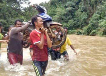 PENDUDUK Orang Asli terpaksa bergotong-royong mengangkat motosikal selepas beberapa tanah runtuh berlaku di beberapa laluan masuk ke penempatan di Pos Gob, Gua Musang, Kelantan-IHSAN PENDUDUK.