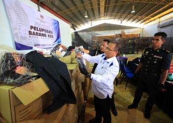 AZMAN Ismail (kiri) memeriksa barangan yang dilucuthak untuk dilupuskan oleh KDPN Kelantan di Kandis Bachok, Kelantan hari ini-UTUSAN/KAMARUL BISMI KAMARUZAMAN