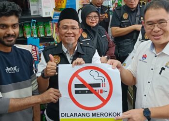 LING TIAN SOON (kanan)  menyerahkan tanda larangan merokok kepada pemilik sebuah kedai di Larkin, Johor Bahru.