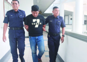 TERTUDUH diiringi anggota polis ketika dihadapkan ke Mahkamah Majistret, Ayer Keroh, Melaka. – UTUSAN/MUHAMMAD SHAHIZAM TAZALI