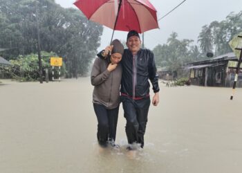 SHANISA bersama bapanya, Mohd. Aqbal Yahya mengharung banjir untuk berpindah ke PPS di Kampung Kampung Buluh, Bandar Permaisuri, Setiu. - UTUSAN/WAN ZURATIKAH IFFAH WAN ZULKIFLI