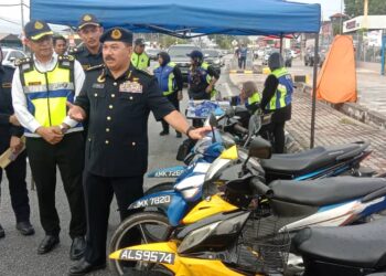 MUHAMMAD Kifli Ma Hassan (depan) menunjukkan motosikal yang disita dalam Operasi Khas Motosikal di Jalan Sitiawan-Seri Manjung hari ini. - UTUSAN