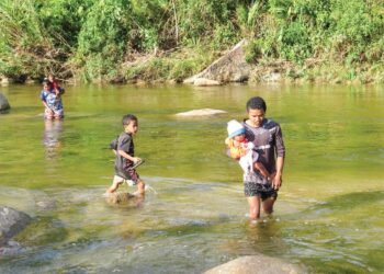 PENDUDUK Orang Asli di tiga kampung di Pos Gob, Gua Musang meredah Sungai Puian kerana ketiadaan jalan penghubung atau jambatan untuk ke kampung berhampiran. – UTUSAN/AIMUNI TUAN LAH