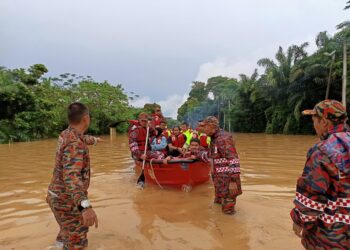 ANGGOTA bomba menyelamatkan mangsa terjejas banjir dari Kampung Sungai Kelamah, Tampin untuk dihantar ke PPS berhampiran.-UTUSAN/NOR AINNA HAMZAH.