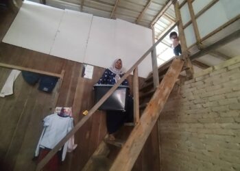 NIK Azizah Nik Mohd. mengangkat barang untuk disimpan di loteng rumahnya di Kampung La, Hulu Besut, Besut, semalam. – UTUSAN/WAN ZURATIKAH IFFAH WAN ZULKIFLI