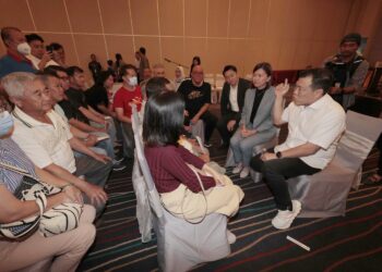 LOH Sze Yee (kanan) bercakap dengan petani yang menerima pembayaran ex-gratia di Ipoh semalam. - UTUSAN