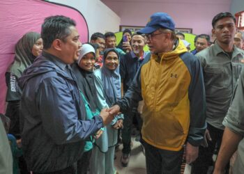 ANWAR Ibrahim (kiri) menyantuni mangsa banjir ketika melakukan lawatan di PPS SK Telaga Papan, Setiu, hari ini. - UTUSAN/PUQTRA HAIRRY ROSLI