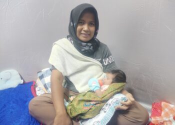 NORATIKAH Mohd. Rosdi memangku bayinya ketika berada di PPS SK Permaisuri, Setiu, hari ini. - UTUSAN/WAN ZURATIKAH IFFAH WAN ZULKIFLI