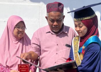 NUR AFIKA Idris (kanan) menunjukkan ijazah yang diterimanya dalam Konvokesyen UTHM Ke-24 kepada ibu dan ayahnya di Batu Pahat.