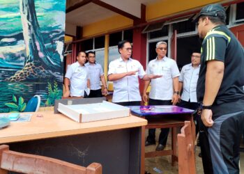 AZMAN Adnan (tiga dari kiri) melihat bahan-bahan pembelajaran dan peralatan sekolah yang musnah ditenggelami banjir di Sekolah Menengah Kebangsaan Bukit Payung di Besut, Terengganu semalam,