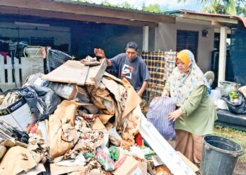 ANNUR Najiha dan suaminya membuang barangan yang rosak ditenggelami banjir di kediamannya di Taman Rakyat, Dungun, Terengganu semalam. – MINGGUAN/NIK NUR IZZATUL HAZWANI NIK ADNAN