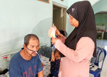 NUR SHAFIQA Abdul Rahim memberi susu khas kepada Mohd. Hamdan Che Mat melalui tiub di Kampung Kuala Lanar di Lipis, Pahang.