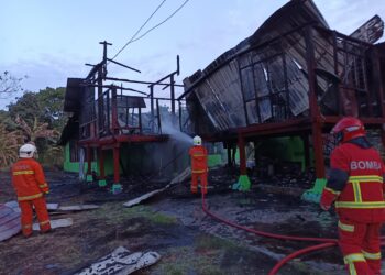ANGGOTA bomba memadamkan kebakaran membabitkan sebuah rumah di Kampung Rendah, Pedas, Rembau petang tadi.-UTUSAN/NOR AINNA HAMZAH.